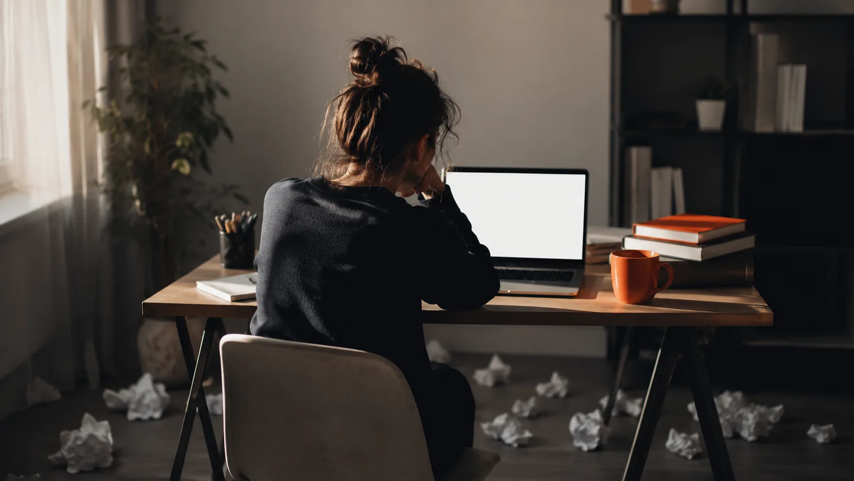 Beginner content creator facing writer's block at their desk, illustrating the starting point for AI writing tools.