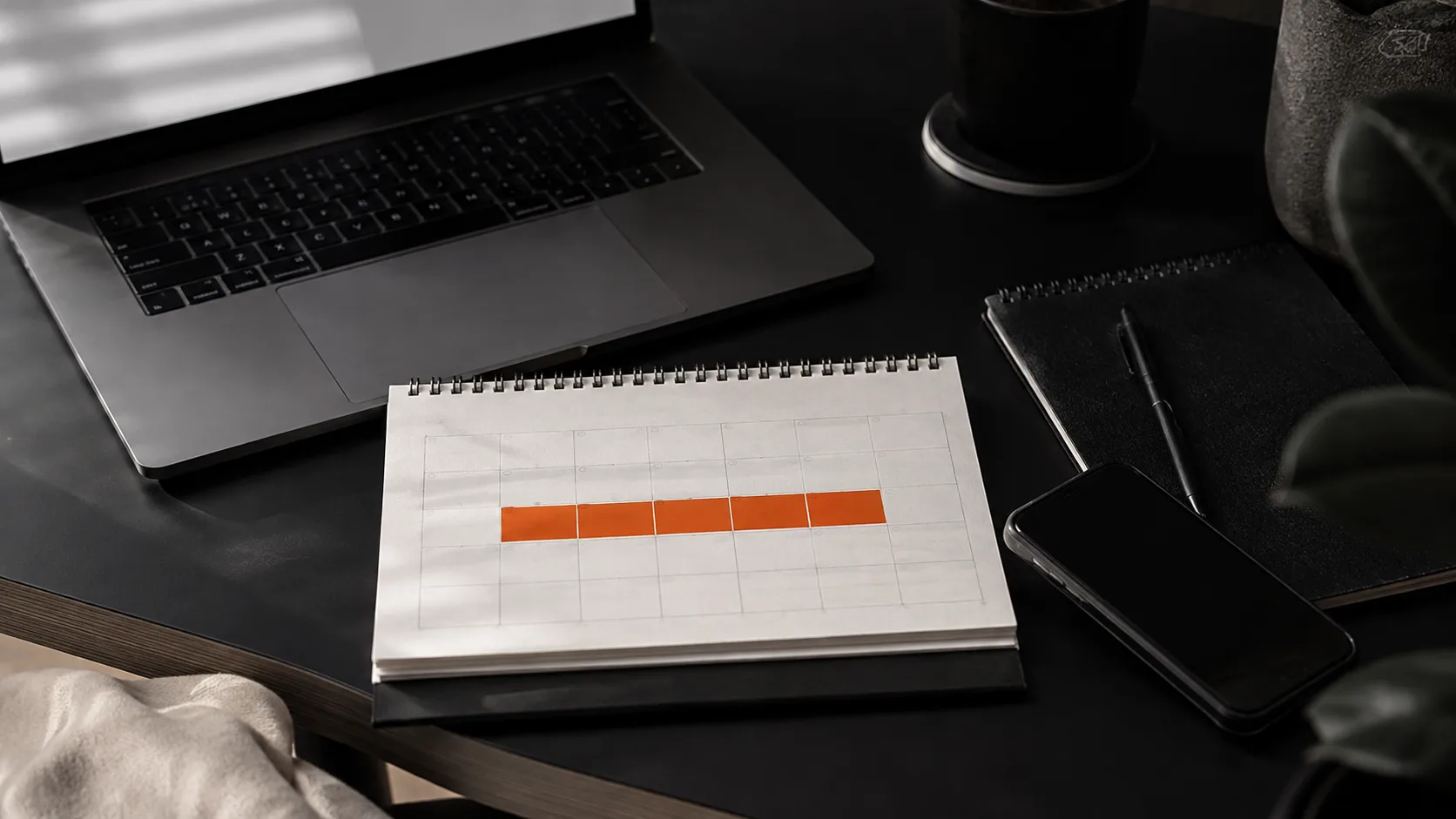 Minimalist workspace showing a calendar, laptop, and notebook symbolizing time commitment for passive income setup.