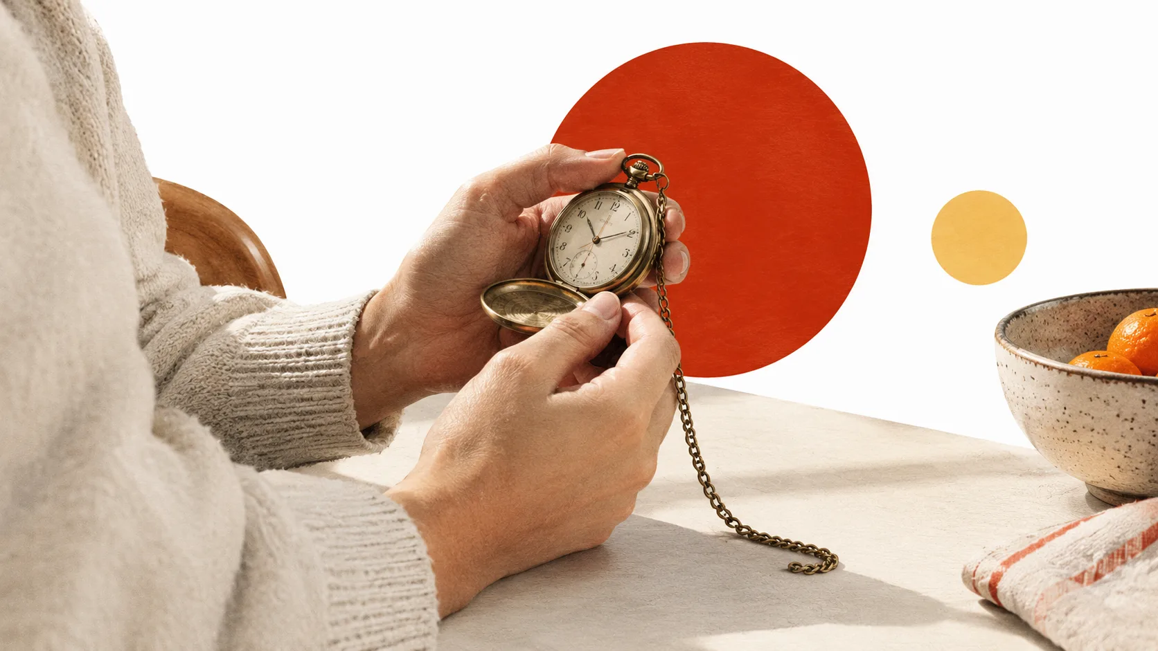 A person holds an open pocket watch beside a bowl of oranges.